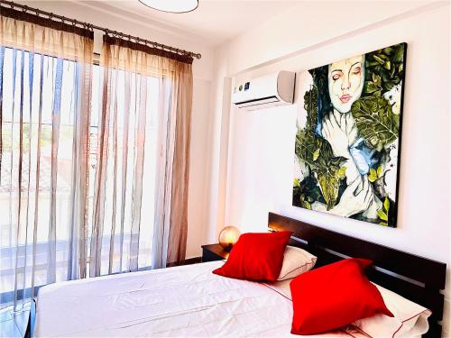 拉纳卡BALI SUITES 101的卧室配有红色枕头,床上方有大画作