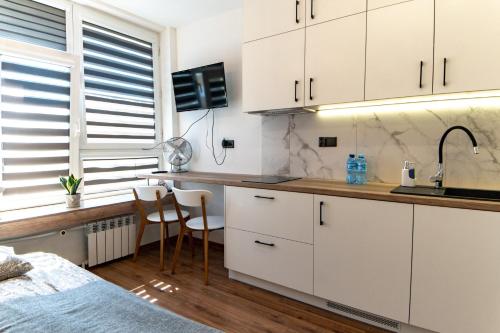 拉多姆Komfortowe studio ścisłe centrum Radom的一间厨房,配有白色的橱柜和一张位于客房内的床