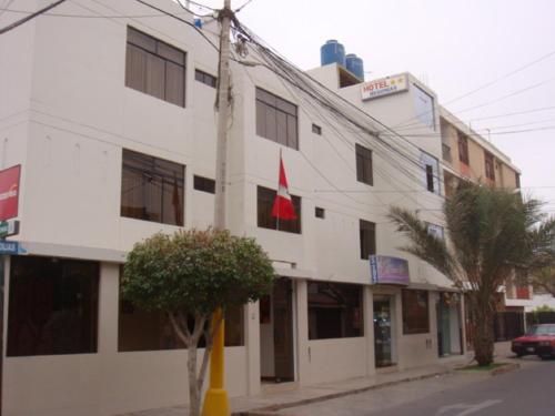 LambayequeHotel Begonias的前面有红旗的白色建筑