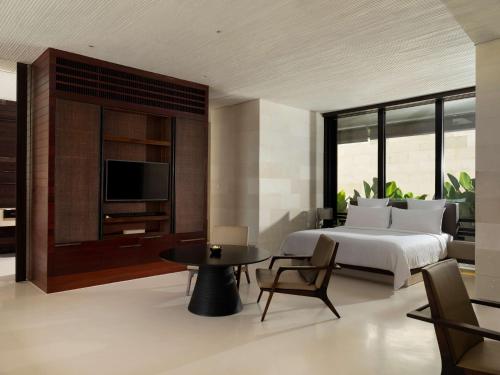 乌鲁瓦图阿丽拉别墅乌鲁瓦图的一间卧室配有一张床、一台电视和一张桌子