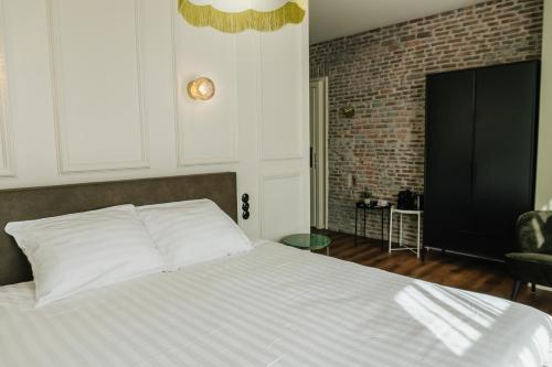 吕伐登In de Brouwerij的卧室配有白色的砖墙床