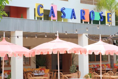 曼德琉-拉纳普勒Hotel Casarose - Cannes Mandelieu的餐厅前的两把粉红色遮阳伞