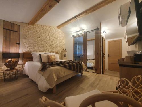 JaujacLa babounette的一间卧室设有一张大床和石墙