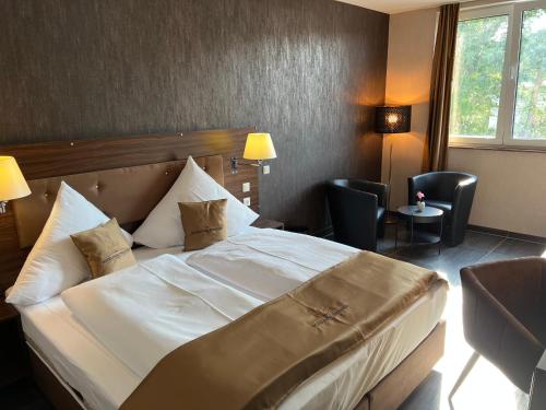 美茵河畔哈瑙Hotel Pasa Paradies KOSTENLOSE PARKPLÄTZE的酒店客房带大型白色床和椅子