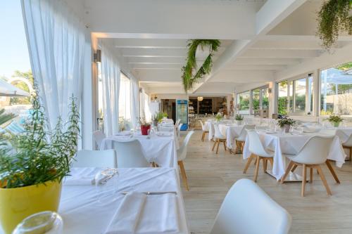 维耶斯泰Malia Village的餐厅设有白色的桌椅和窗户。
