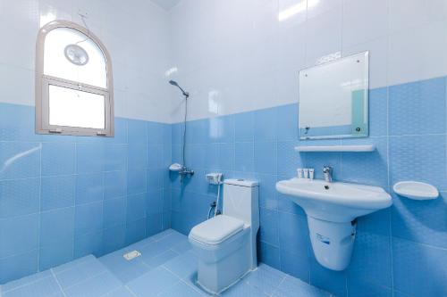阿尔哈德Super OYO 110 Ras Al Hadd Guest House的蓝色的浴室设有卫生间和水槽