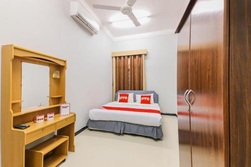 阿尔哈德Super OYO 110 Ras Al Hadd Guest House的一间卧室配有一张床、一张书桌和一面镜子