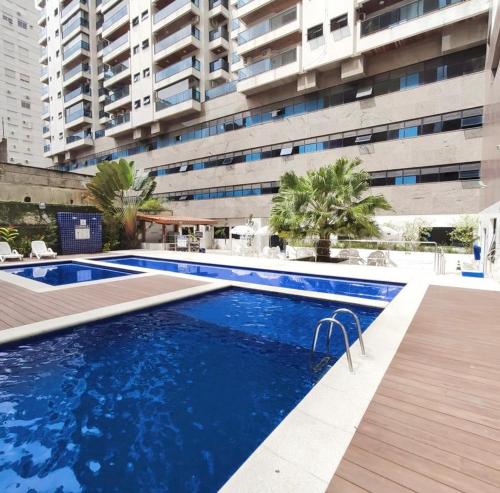 瓜鲁雅NOVO Capitânia Varam 2, dois dormitórios, piscina, churrasqueira, duas vagas de garagem的一座大建筑前的游泳池