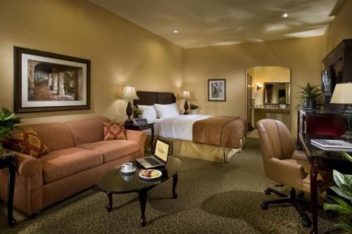 雷德兰兹Ayres Hotel Redlands - Loma Linda的酒店客房配有床、沙发和桌子。