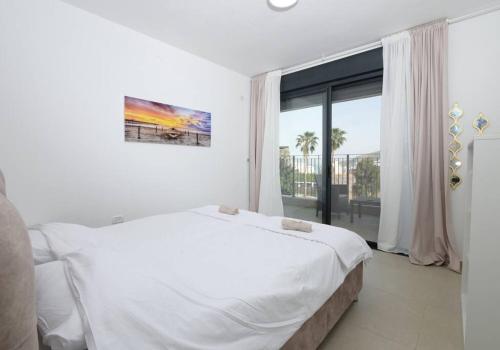 提比里亚אצולת הים - טבריה的白色的卧室设有一张大床和一个大窗户