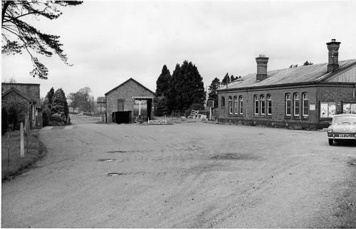 赫里福德The Booking Office, Stoke Edith Station的建筑物旁一条土路的黑白照片