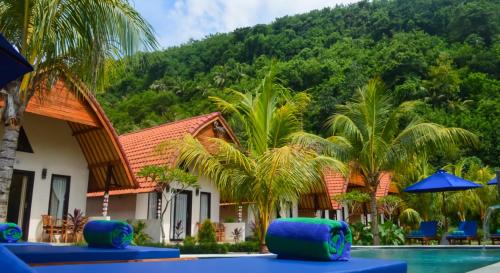珀尼达岛Penida Bay Village的一个带游泳池和棕榈树的度假村