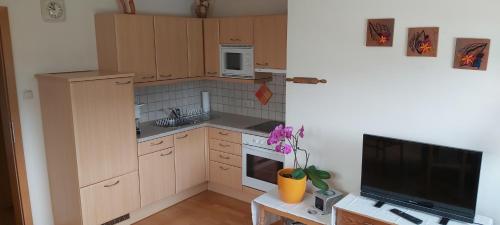 玛利亚采尔Haus Zach的厨房配有木制橱柜、电视和桌子。