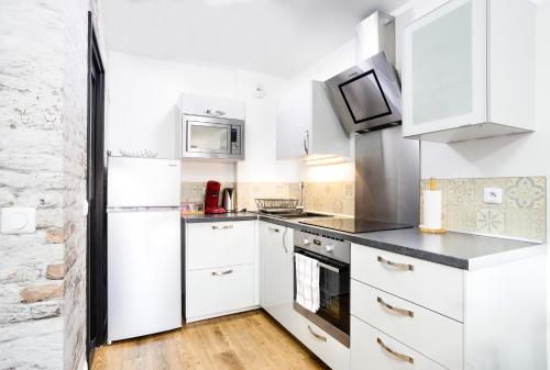 达马利百合APPART PREMIUM DU LYS Balcon amenage Parking gratuit的白色的厨房配有白色橱柜和电器