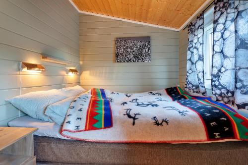 KjøllefjordDavvi Siida - Reindeer Design Lodge的一间卧室配有一张带床罩的床和窗户