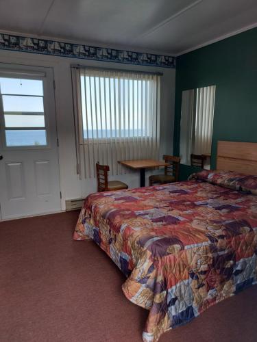 CloridormeMotel du Cap St-Yvon的一间卧室配有一张床、一张桌子和一个窗户。