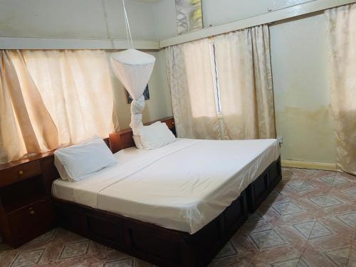 Bakau世界大同旅馆的一间卧室配有一张带白色床单的大床
