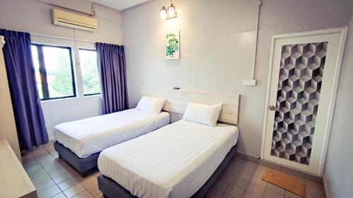 马六甲莲花旅馆的带2扇窗户的客房内的2张床