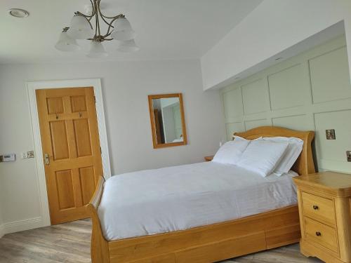 CarnmalinBiddy Ban’s的一间卧室配有一张带白色床单和镜子的床