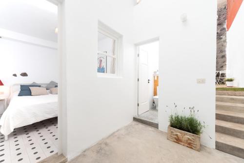 加拉奇科Casita tradicional canaria en Garachico - SanRoquito18的卧室拥有白色的墙壁和一张床,设有楼梯