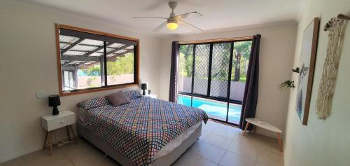 彩虹海滩Bomburra 6的一间卧室设有床、两个窗户和一个游泳池