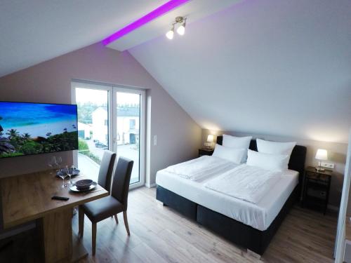 富尔达-Neubau- 30qm Dach-Apartment的一间卧室配有一张床、一张书桌和一台电视。