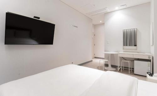 首尔新大田H大道酒店的白色的客房配有床、书桌和电视。