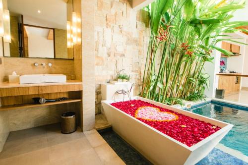 沙努尔The Mavila - CHSE Certified的浴室配有装满红花的浴缸。