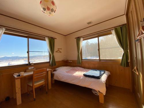 Matsukawa安昙野背包客旅馆的卧室配有一张床、一张书桌和窗户。