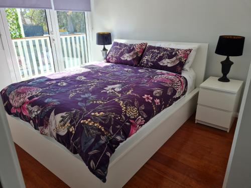 沃加沃加Alkion Villa的一张带紫色棉被和窗户的床