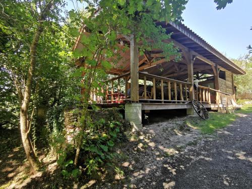 米奥Le Tipi Ethnique au bord de la rivière的木房子,树林里设有门廊