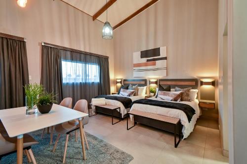 布隆方丹Summer PALACE Guesthouse的配有两张床铺的客房配有桌椅