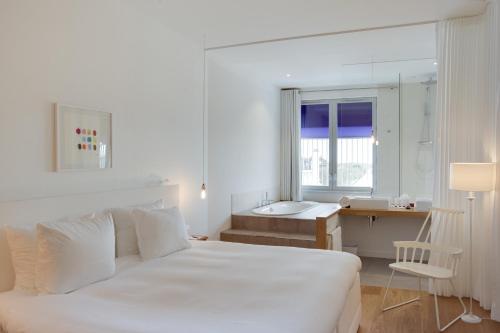 海滨诺德韦克瓦思派尔酒店的白色的卧室设有床、书桌和窗户