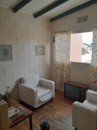 乌拉圭河畔康塞普西翁Parivaar Host的客厅配有白色椅子和电视