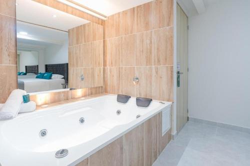 麦德林Hotel Urbano 70的一间带浴缸和大镜子的浴室