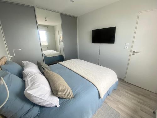 滨海贝尔克Appartement de standing VUE MER的一间卧室配有带枕头的床铺和电视。