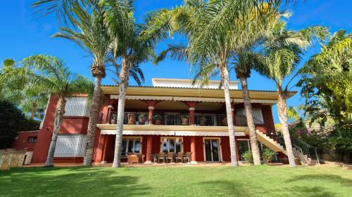 穆特克萨梅尔10 Bedroom 5 Star Luxury Villa & Heated Pool for 5 to 30 Guests near Alicante的一座棕榈树的红色房子