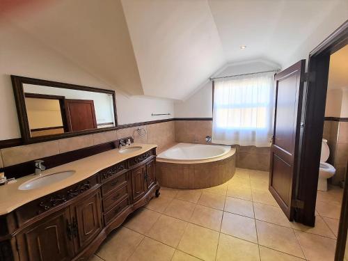 诺丁汉路One Rawdons Estate的一间带两个盥洗盆、浴缸和卫生间的浴室