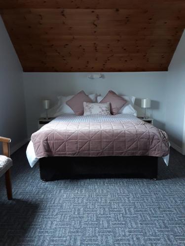 基拉尼Greenmount Accommodation的一间卧室设有一张带木制天花板的大床