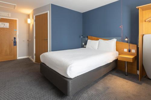 阿伯丁快捷假日阿伯丁市中心酒店的一间卧室设有一张蓝色墙壁的大床