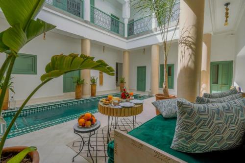 马拉喀什Riad Trésor Marrakech的客厅设有游泳池和带水果的桌子