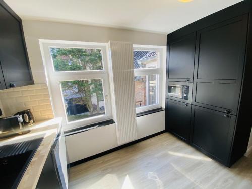 德哈恩Lovely, renovated appartment, near the beach.的厨房配有黑色橱柜和2扇窗户。