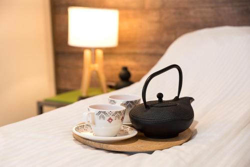 克卢日-纳波卡Ultra Central Bohemian Apartment 1的床上的托盘,上面有2杯和茶壶