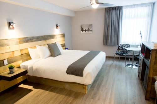 Val-MorinHôtel Far Hills的酒店客房设有一张大床和一张桌子。