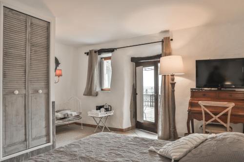 Saint-Laurent-du-PapeMaison d'hôtes Le Hameau de la Mûre的一间卧室配有一张床、一台电视和一架钢琴