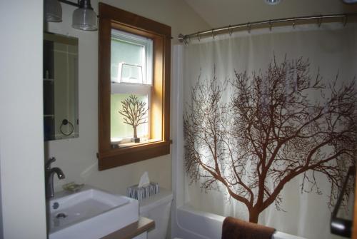 伦弗鲁港狂野海岸度假屋的浴室设有淋浴帘,上面有一棵树