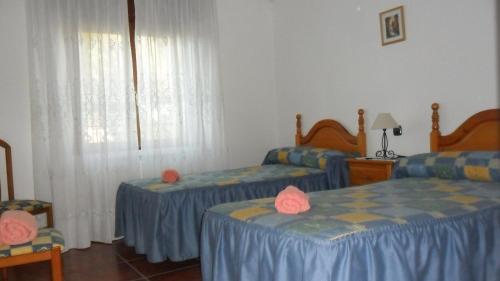 Piña de CamposCasa Rural El Arrabal的一间卧室设有两张床、两把椅子和窗户。