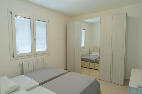 波扎洛Raganzino Apartment Pozzallo - new building的一间白色卧室,配有两张床和镜子