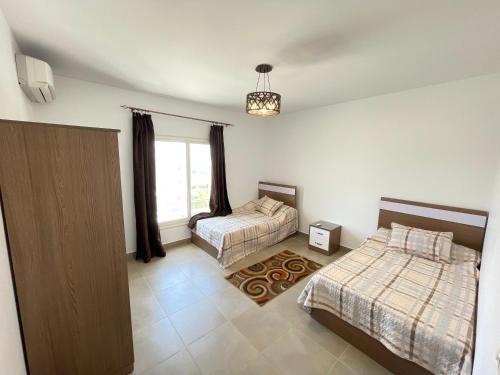 阿莱曼Amwaj Seaside Retreat- Luxury 2BR Chalet in Amwaj Sidi Abdelrahman的一间卧室设有两张床和窗户。