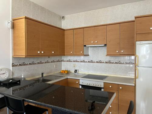 宏达海滩Apartamento Playa Honda的厨房配有木制橱柜和黑色台面